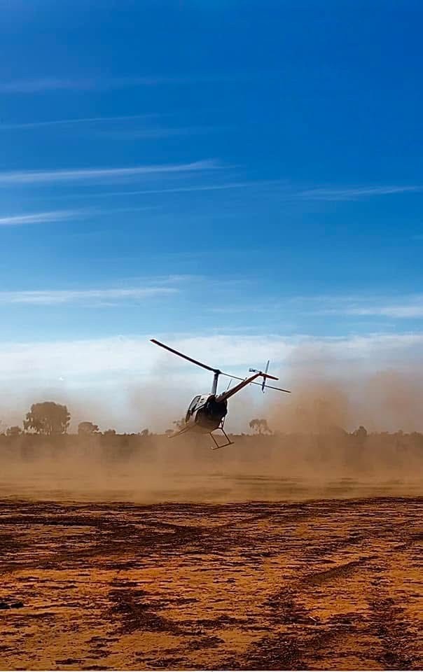 The helicopter lifting off in red dust